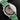 angled studio top-down view of the Hermès Squelette Lune watch highlighting its polished bezel and vibrant green leather strap
