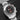 Front-angled view highlighting the bold red central chronograph timing hands and the signature multi-link stainless steel sports bracelet