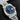 close-up studio portrait focusing on the blue dial, white gold Roman numeral indices, and the date indicator window magnified by the cyclops lens